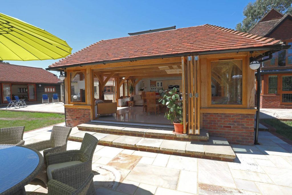 An oak framed house extension on sunny patio with the doors open