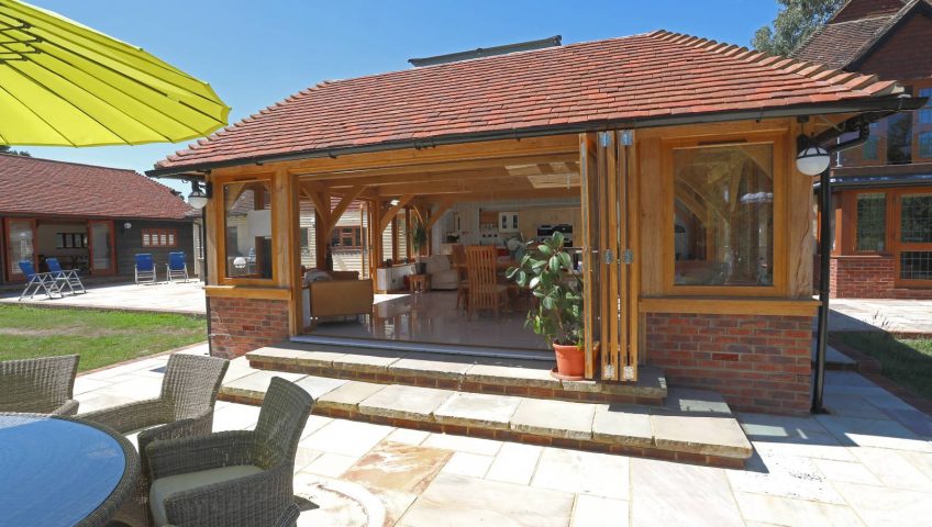 An oak framed house extension on sunny patio with the doors open